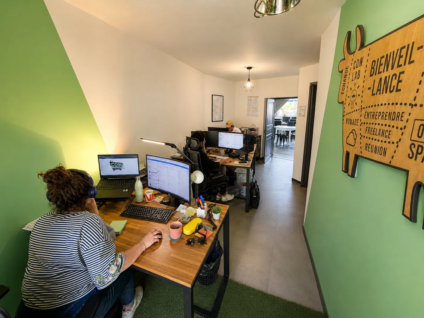 Espace de coworking chaleureux avec bureaux, lumière douce et panneau en bois